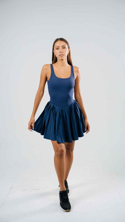 Full-length front view of the Courtney navy padel dress with fitted top and pleated skirt